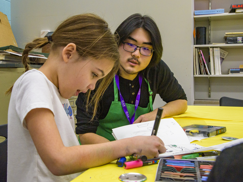 Child drawing with Naz student supervising