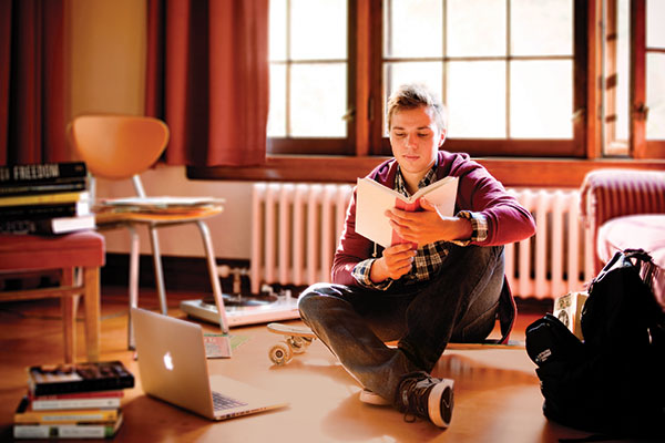 student sitting on the floor reading a book