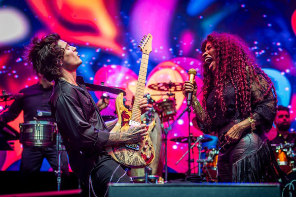 Jon Dretto & Chaka Khan performing onstage with vibrant colors onscreen behind