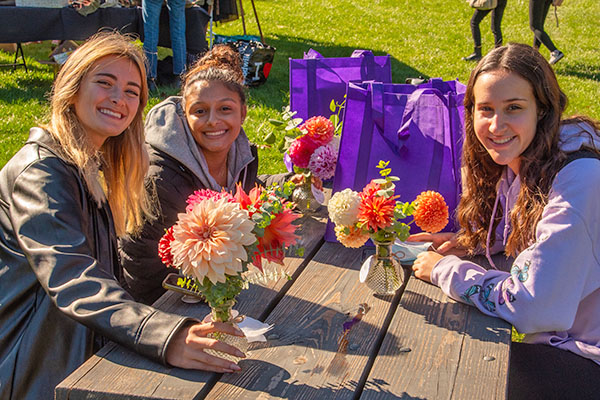 students with flowers in vases sitting at a picnic table