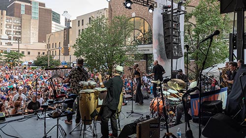 Community Soul Project band performs onstage in Rochester before a large outdoor audience