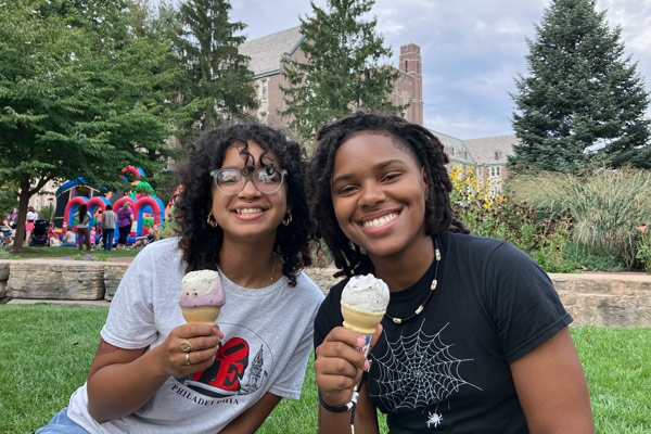 Two people pose with ice cream with inflatables and Golisano Academic Center behind