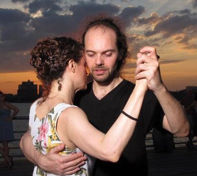 Octavio Vazquez dancing tango with a partner outside, with a sunset behind