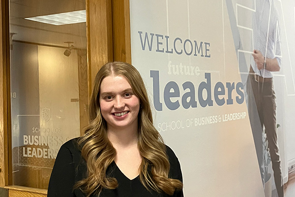 Emily Tyo poses by a School of Business and Leadership mural and offices