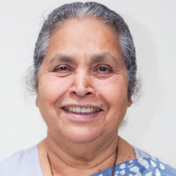 Lucy Kurien in an outfit with a blue-and-white patterned fabric draped over her shoulder. 