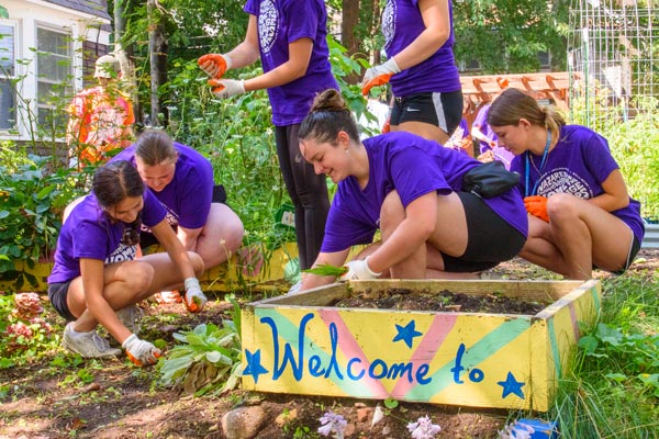 student volunteers gardening in the community in purple Naz shirts