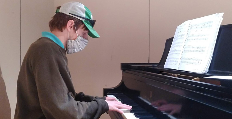 Paul Gaston playing piano, wearing a mask, during the COVID-19 pandemic
