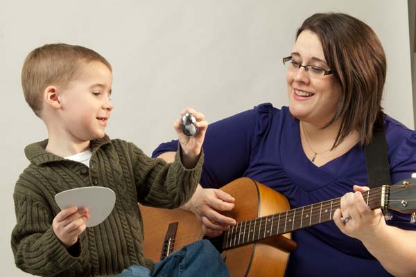 music therapy student with guitar, child with percussion shaker