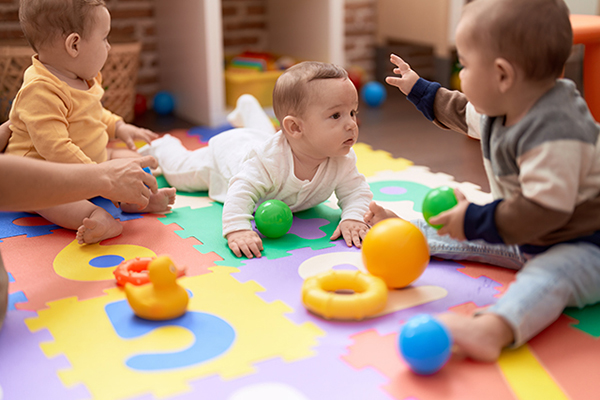 babies playing with toys on a colorful mat