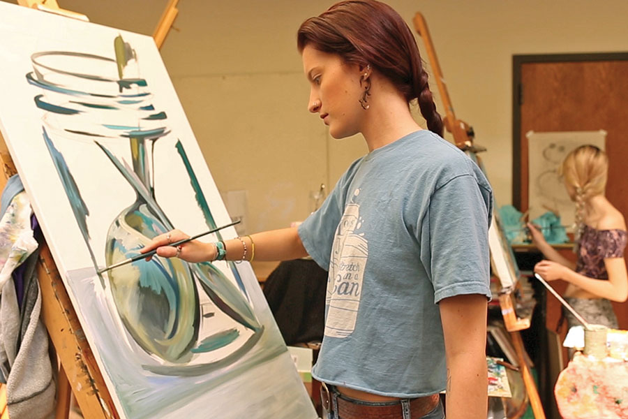 student painting on canvas using easel