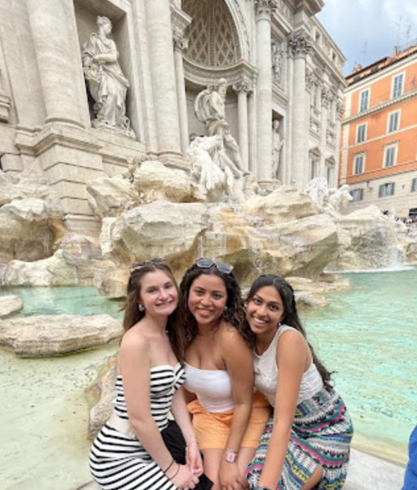 three students pose by a fountain abroad