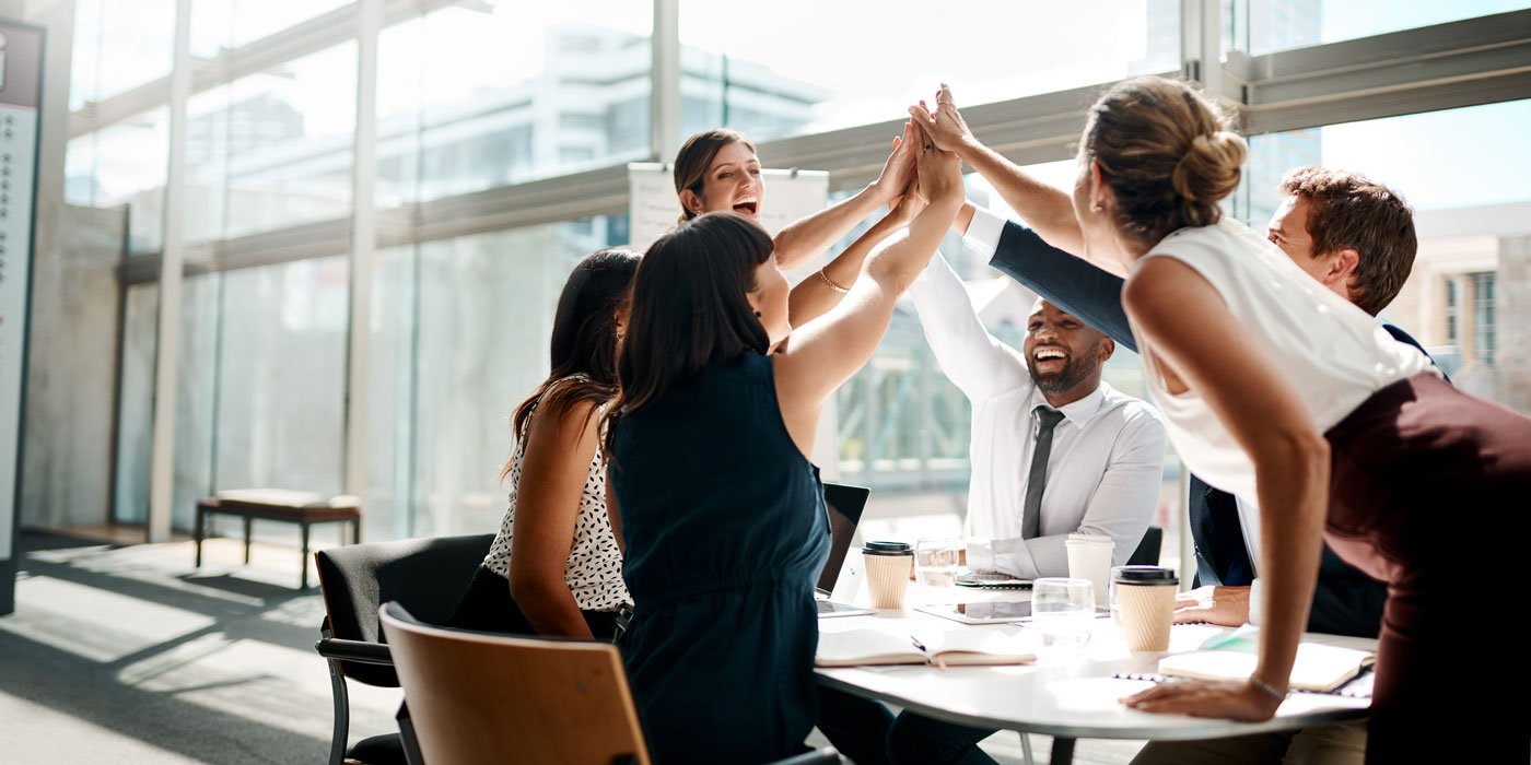 group of people high fiving in a business setting