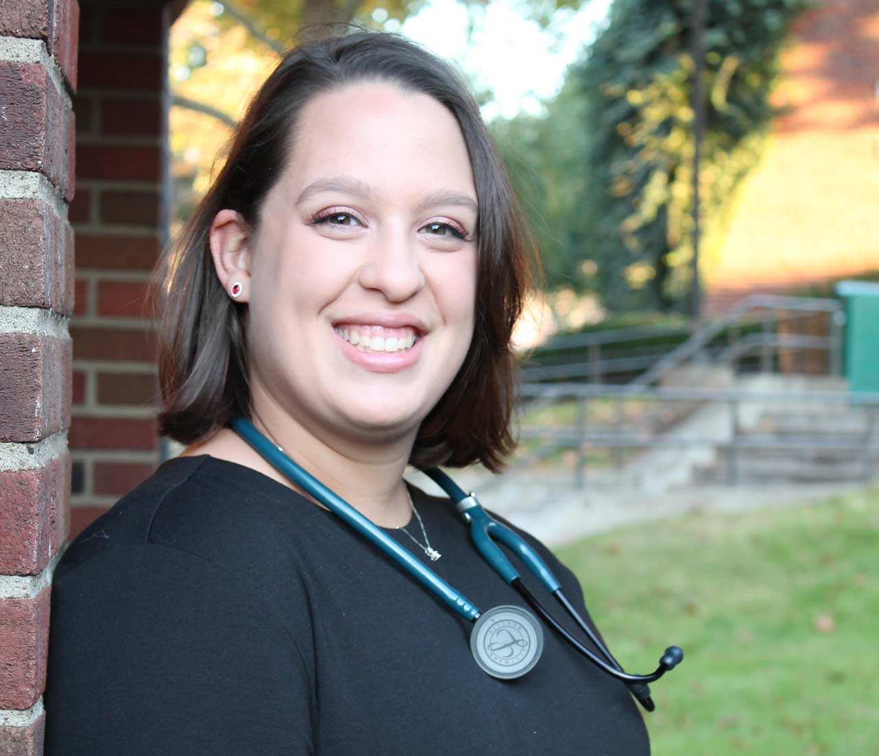 Susan Rollinson poses on campus with stethoscope
