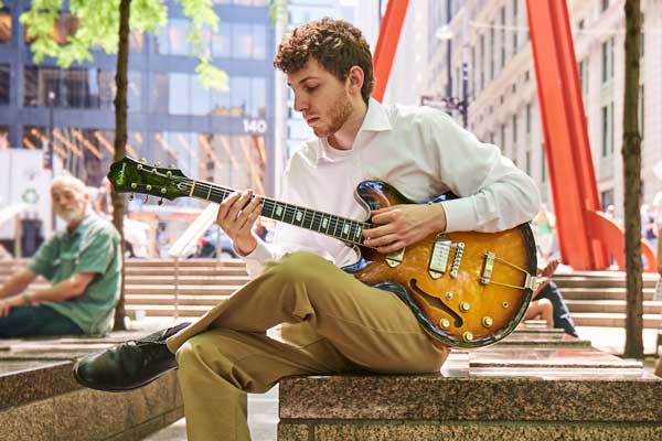 Sean Saville playing guitar in NYC park