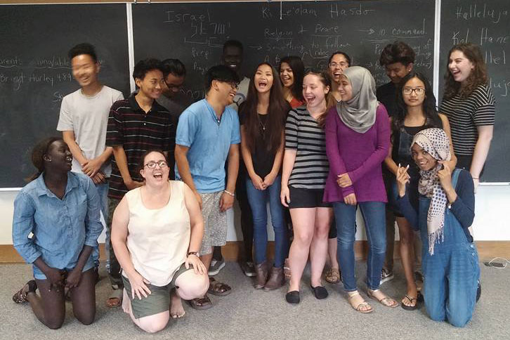 Global Citizenship Immersion students laugh and interact, posing as a group in a classroom
