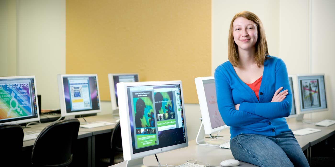 an academic setting featuring a woman positioned in front of three computer screens