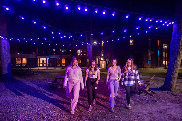 students walking outside under a string of purple lights