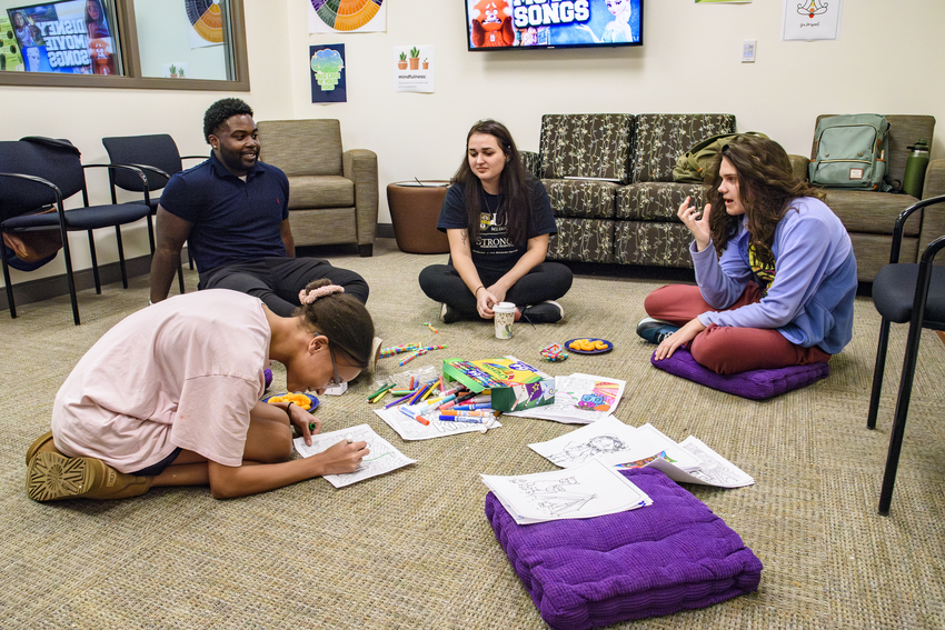 Teens sit in a circle on the carpet with Nazareth students for group therapy