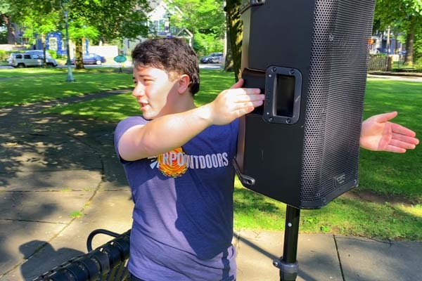 Intern Kyan Cheung sets up a speaker at an outdoor Rochester Philharmonic Orchestra performance