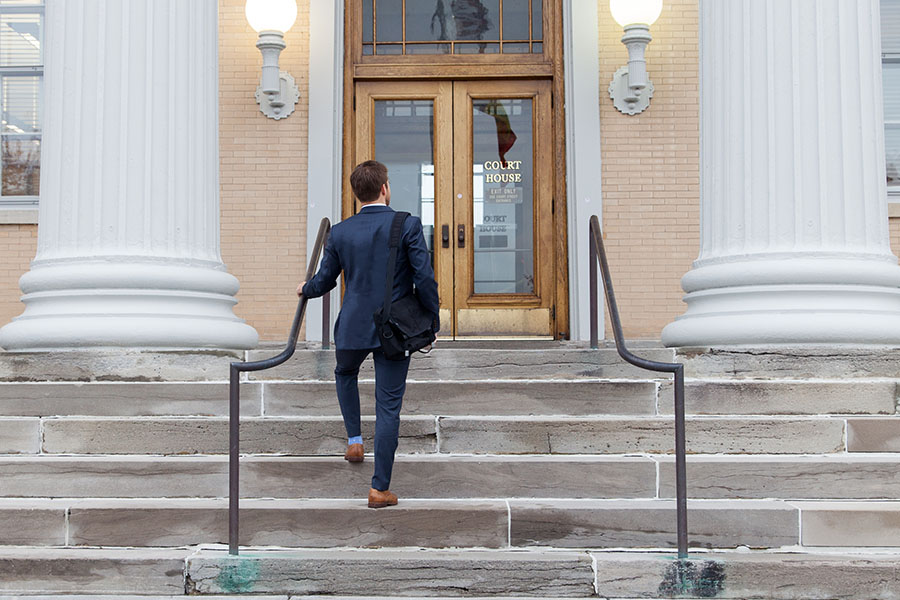 student in a suit entering a court house