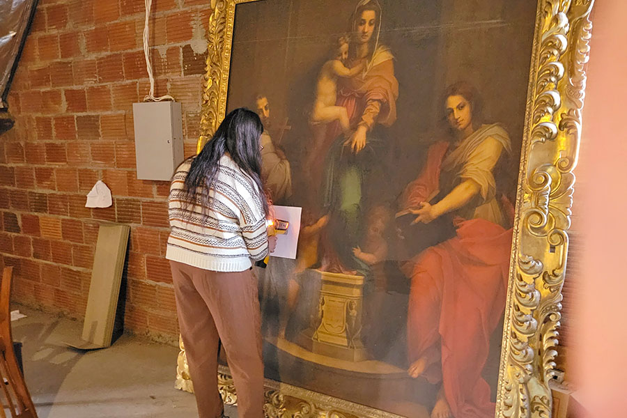 Addison Wallace performing light analysis on large painting