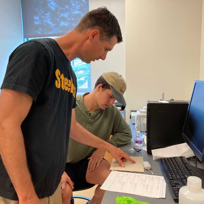 Prof. Stephen G. Tajc (standing) confers with student Andrew Vogler on his summer research work.