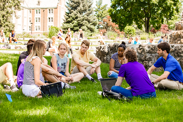 student group seated on the lawn near a fountain