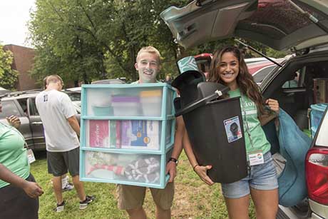 A student carrying a tote box as they move into their residence hall.