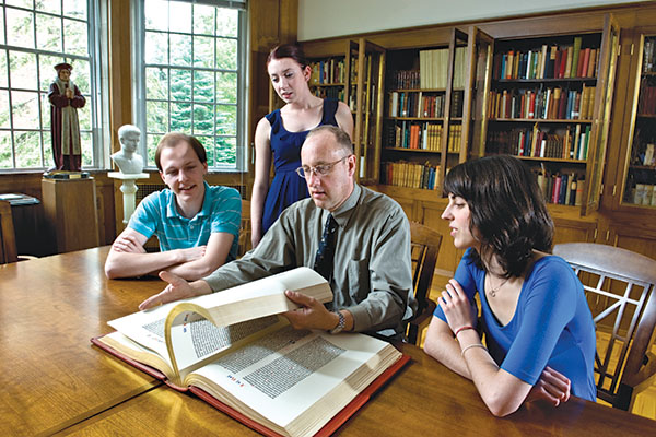 professor showing historical book to students