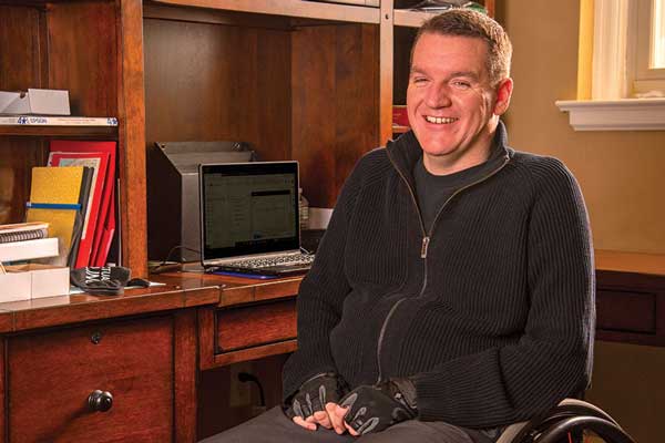 Chris Hilderbrant, in a wheelchair, in his office
