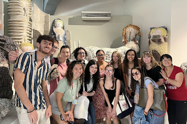Students pose in front of clay sculptures at a museum in Italy