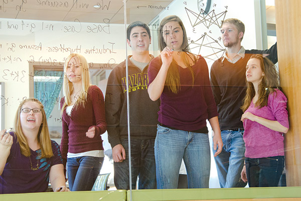 students writing math equations on glass wall