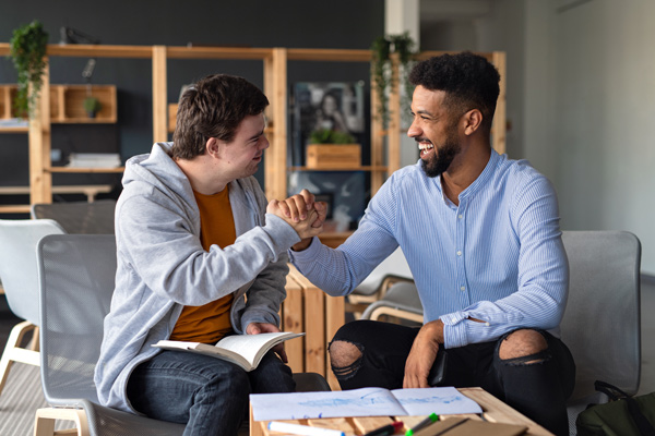 two men clasp hands and smile