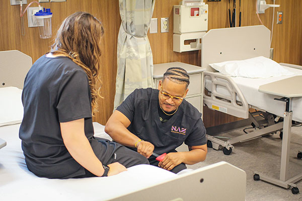 PA student using a reflex hammer on a patient's knee