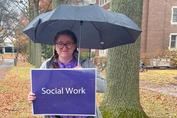 Emma Maskell holds a sign saying social work