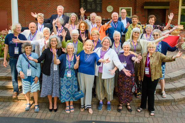 Former faculty & staff pose in a group with their arms out and big smiles