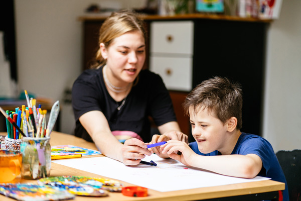boy crayons with adult illustrating an interaction in applied behavioral analysis