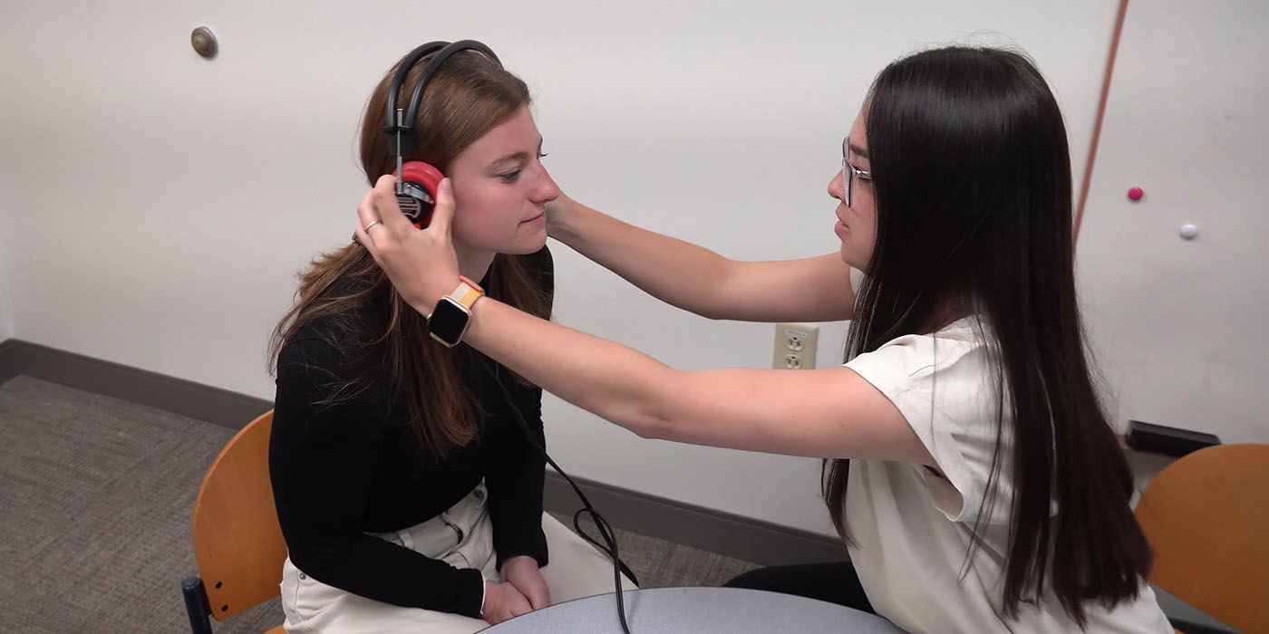 a student placing headphones on another person