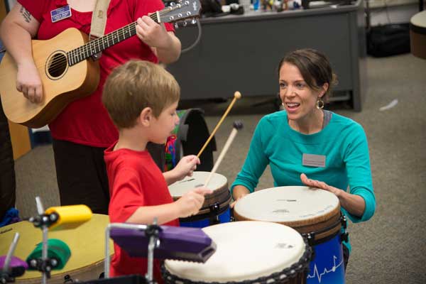 student teaching child to play drums