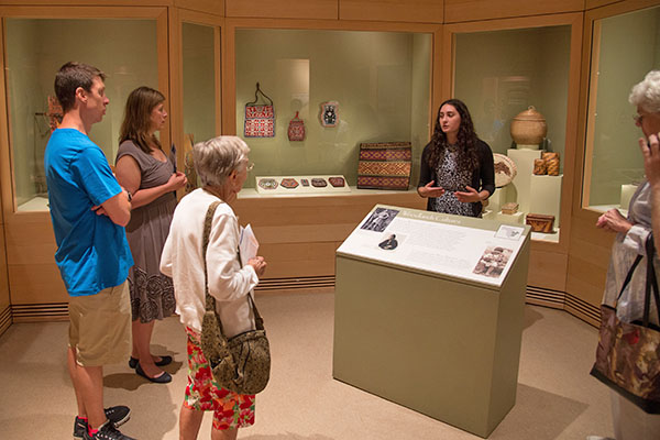 student docent explaining exhibit to museum visitors