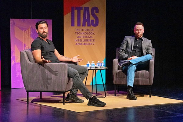 Travis Steffen and Jeff Allan seated on stage speaking to an audience