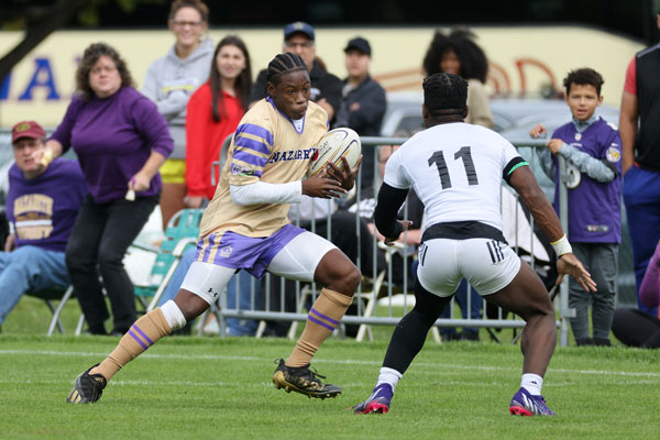 Tyreek Thomas looks intent as he runs and avoids a player from the other team during a rugby game