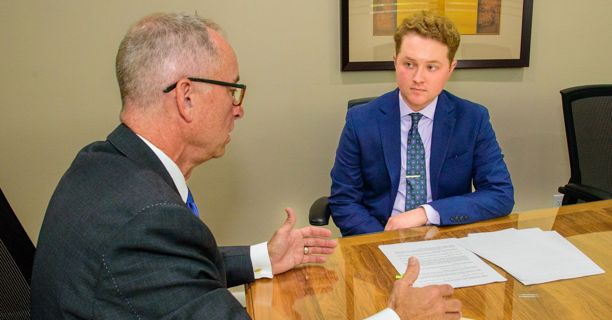 Michael Coles talks with colleague, both wearing suits, at law firm internship.