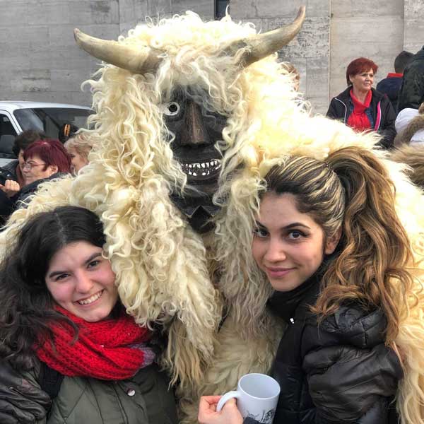 Farida (at right) and another international student enjoy costumed people at Pecs city carnival