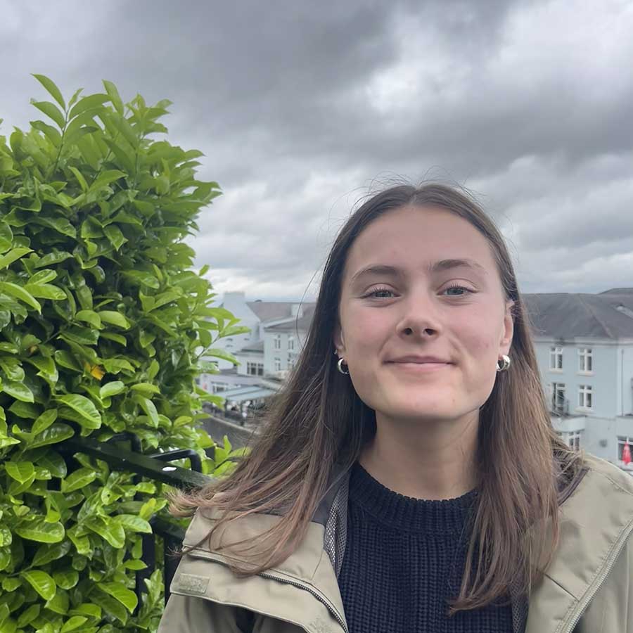 photo of Tatum Overton standing on a balcony in Irleland overlooking a quaint Irish village 