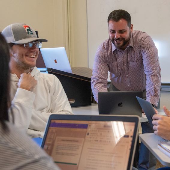 Prof. Bryan Adams and students, each with a laptop, interact in a group