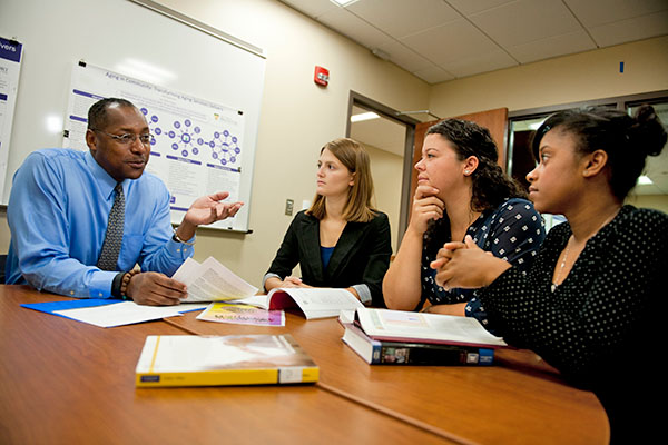 professor conversing with students at a table