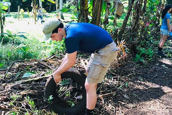 student removing tire from jungle foliage