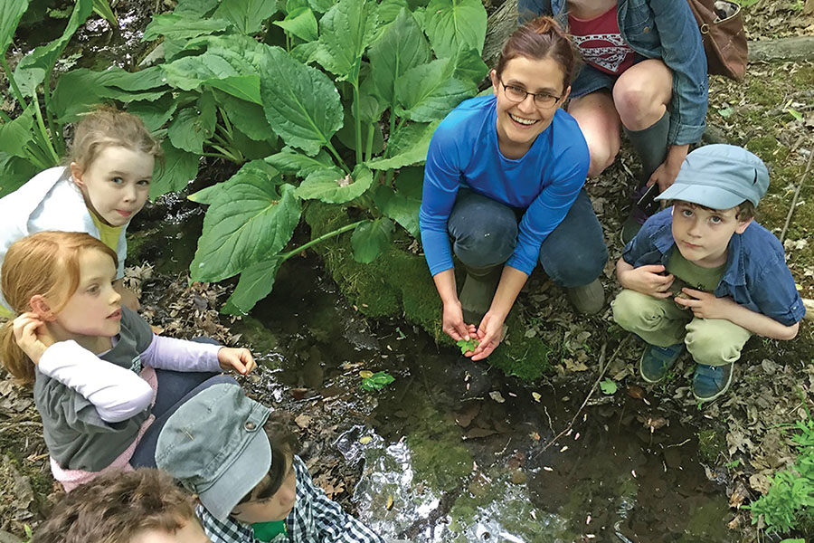 Joanna Dickey in a stream showing foliage to campers