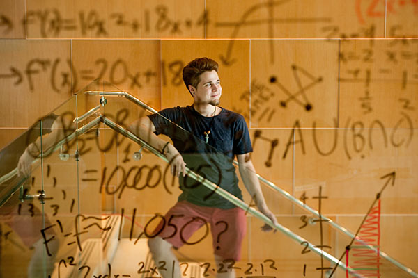 student standing on a staircase with math equations in foreground